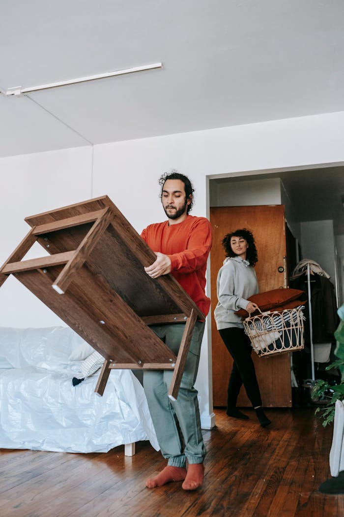 A couple lifting furniture in their home, symbolizing teamwork and moving day.
