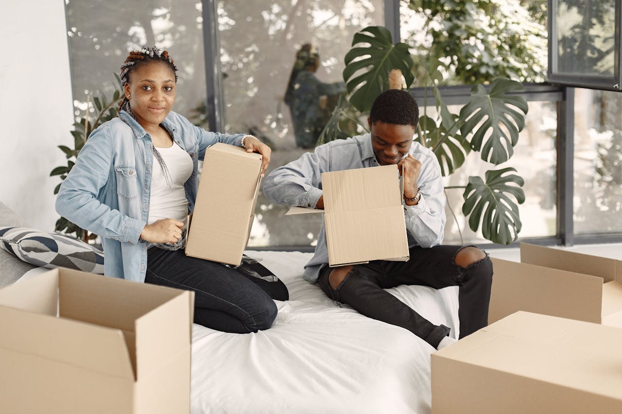 Young couple unpacking boxes in their new home, enjoying the moving process together.