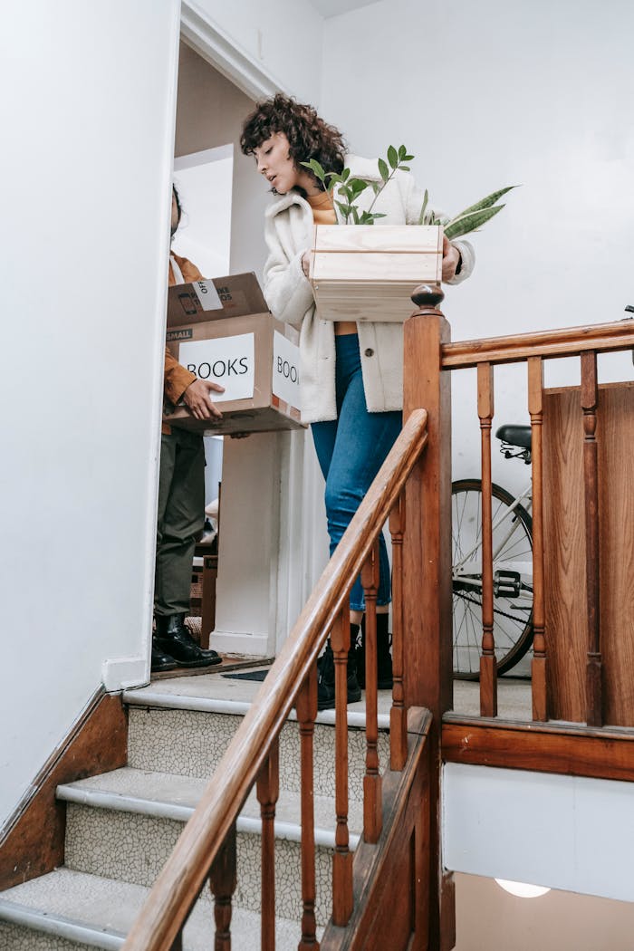 Couple carrying boxes and plants while moving into a new home.